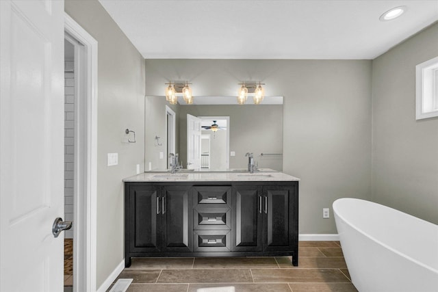 full bathroom with double vanity, a soaking tub, baseboards, and a sink