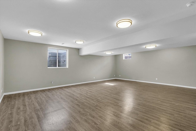 below grade area featuring dark wood-type flooring, visible vents, plenty of natural light, and baseboards