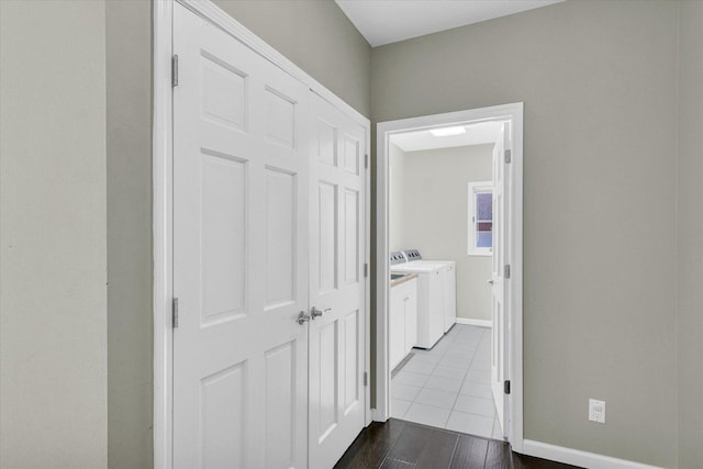 hall featuring light wood-type flooring, washing machine and dryer, and baseboards