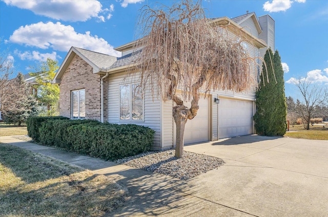 view of side of property with a garage, driveway, brick siding, and roof with shingles