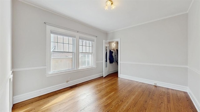 unfurnished room featuring ornamental molding, light wood-type flooring, and baseboards