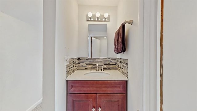 bathroom featuring baseboards, decorative backsplash, and vanity