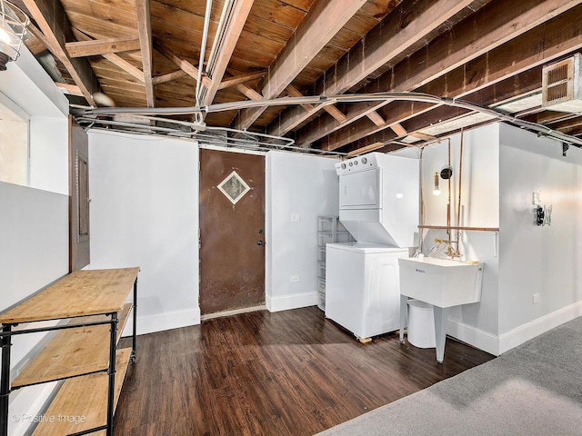 unfinished below grade area with baseboards, stacked washing maching and dryer, and wood finished floors