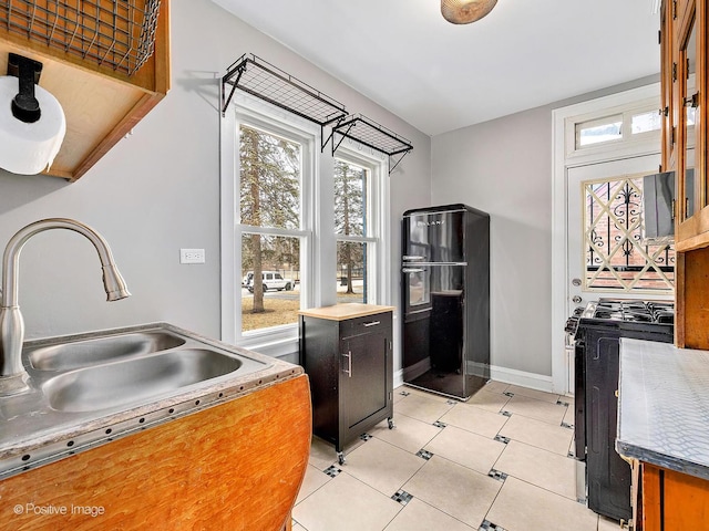 kitchen featuring a healthy amount of sunlight, gas range, light tile patterned flooring, and freestanding refrigerator