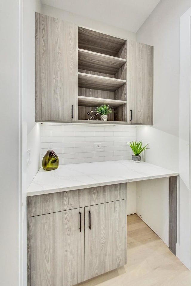 bar with backsplash, light brown cabinetry, and light stone counters