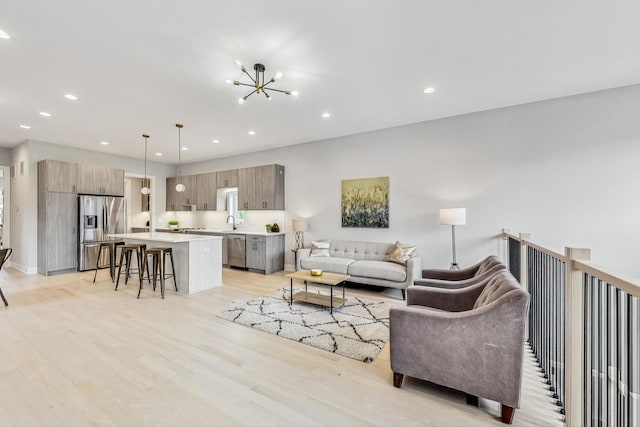 living room with a notable chandelier, sink, and light wood-type flooring