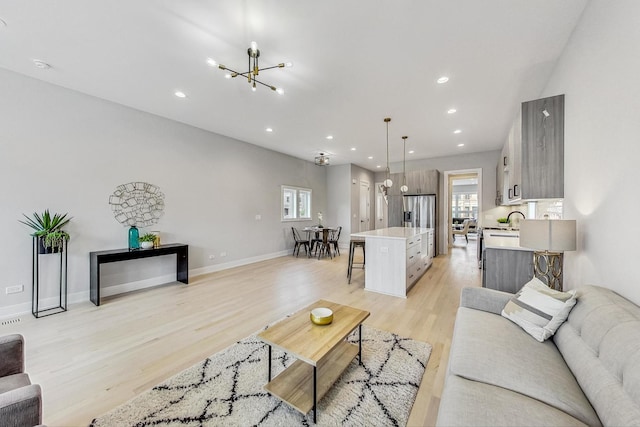 living room with sink, a chandelier, and light hardwood / wood-style flooring