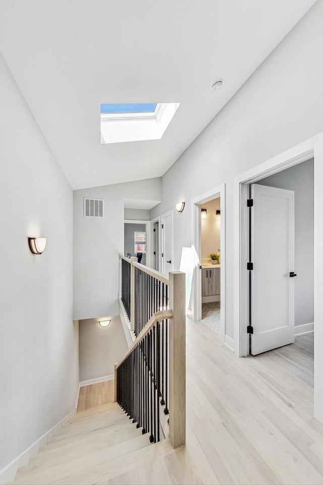 staircase with lofted ceiling with skylight and hardwood / wood-style floors