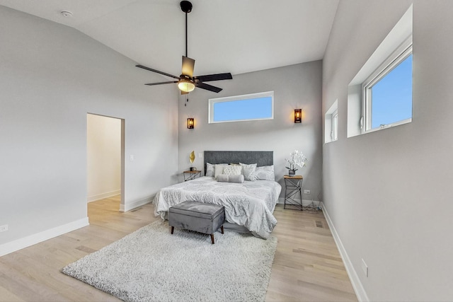 bedroom with ceiling fan, vaulted ceiling, and light wood-type flooring