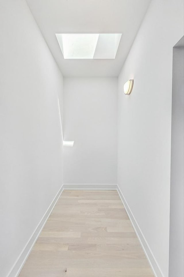 corridor featuring a skylight and light hardwood / wood-style flooring