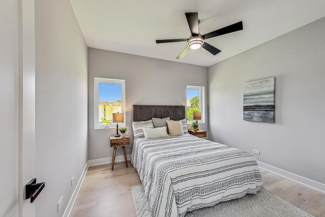 bedroom featuring ceiling fan, multiple windows, and light wood-type flooring