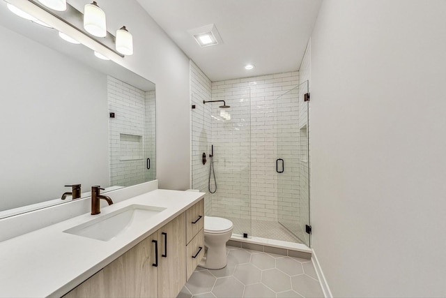 bathroom with a shower with door, vanity, tile patterned floors, and toilet