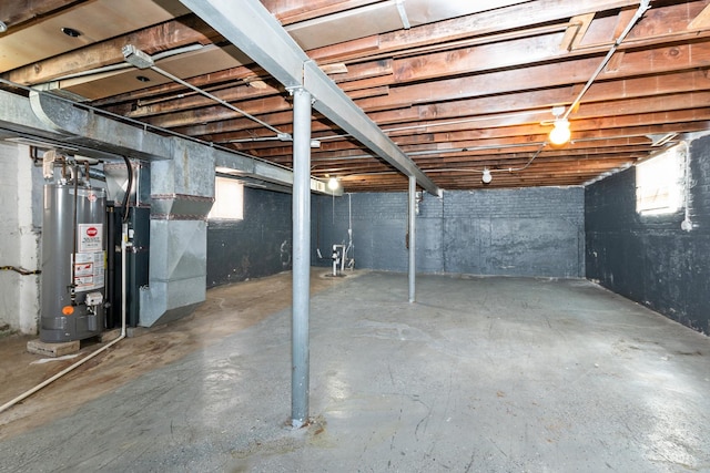 basement featuring heating unit, a healthy amount of sunlight, and gas water heater