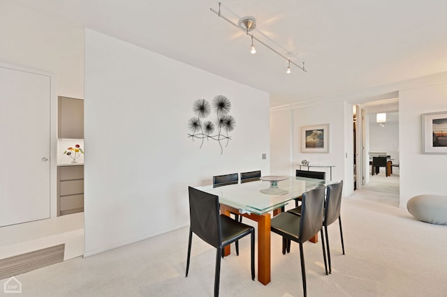 carpeted dining area with track lighting