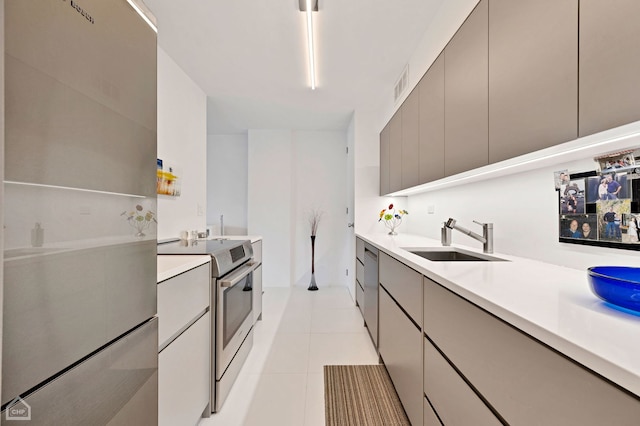 kitchen with sink, appliances with stainless steel finishes, gray cabinetry, and light tile patterned flooring