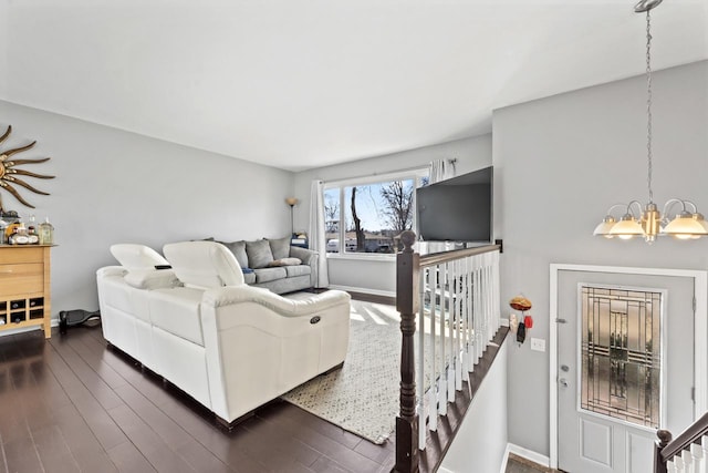 living area featuring dark wood-style flooring, a notable chandelier, and baseboards