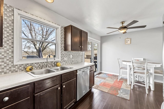 kitchen featuring dark wood-style floors, backsplash, stainless steel dishwasher, a sink, and dark brown cabinets