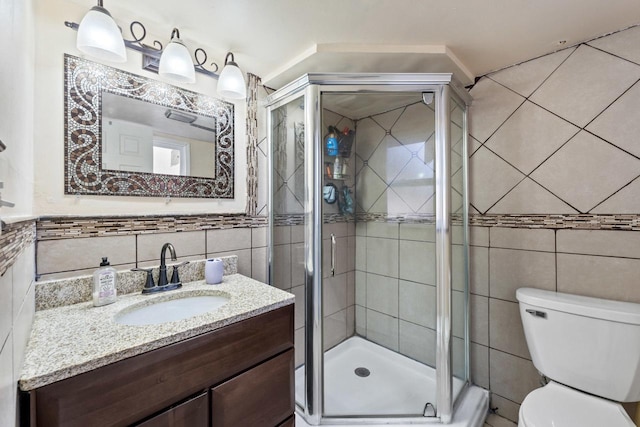 full bathroom featuring toilet, a stall shower, tile walls, and vanity