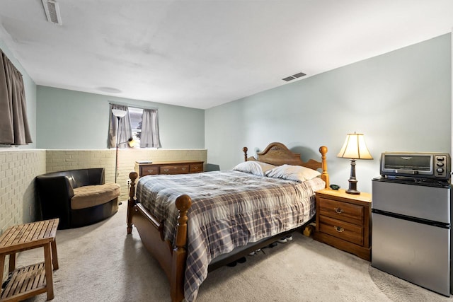 bedroom featuring light carpet, freestanding refrigerator, and visible vents