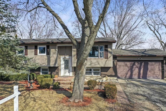 raised ranch with concrete driveway, brick siding, and an attached garage