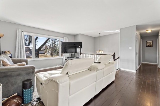 living area featuring a notable chandelier, baseboards, and dark wood-type flooring