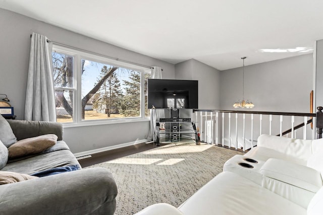 living room with a chandelier, baseboards, and wood finished floors