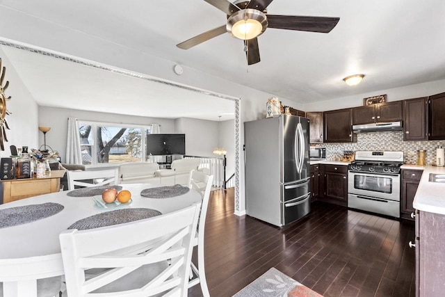 kitchen featuring stainless steel appliances, light countertops, backsplash, dark brown cabinets, and under cabinet range hood