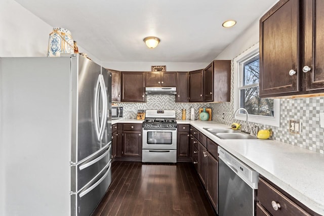 kitchen featuring dark wood finished floors, light countertops, appliances with stainless steel finishes, a sink, and under cabinet range hood