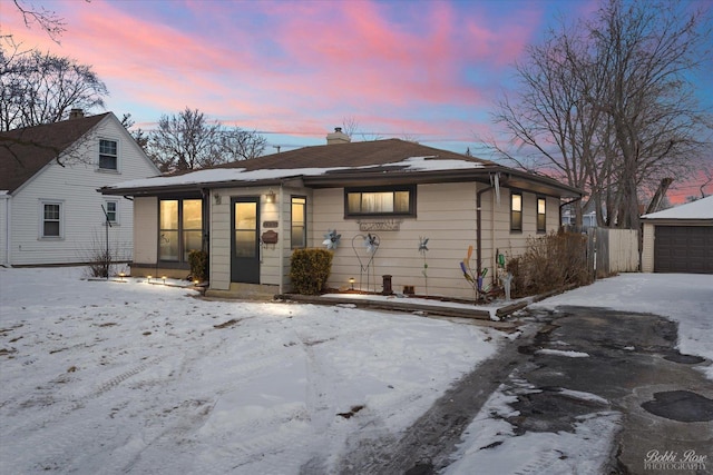 bungalow-style home featuring a chimney and a detached garage