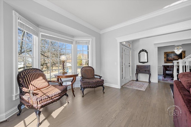 sitting room with baseboards, an inviting chandelier, wood finished floors, and ornamental molding