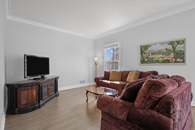 living room featuring visible vents, baseboards, light wood finished floors, and ornamental molding