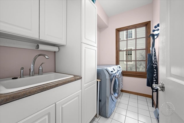 clothes washing area featuring baseboards, washer and clothes dryer, light tile patterned floors, cabinet space, and a sink