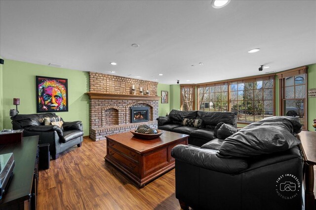 living room featuring visible vents, recessed lighting, a brick fireplace, and wood finished floors