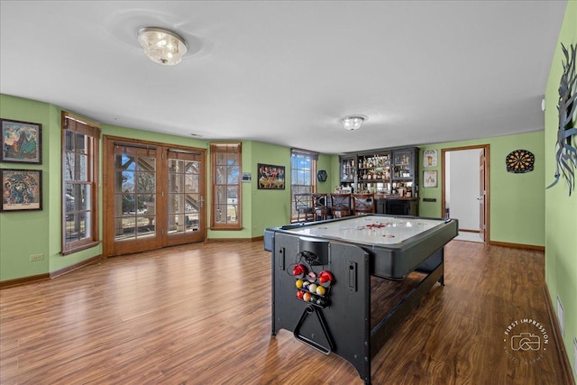 rec room with a bar, wood finished floors, baseboards, and french doors