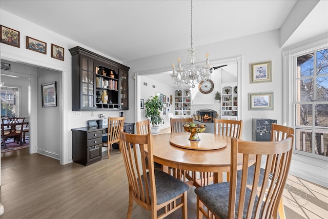 dining area with a wealth of natural light, a chandelier, wood finished floors, and a fireplace