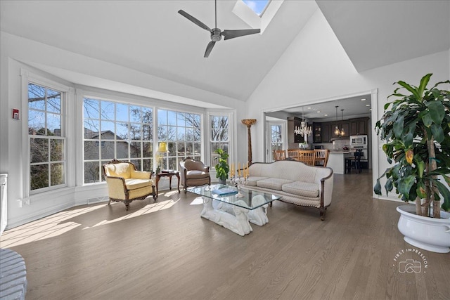 living room with wood finished floors, visible vents, high vaulted ceiling, a skylight, and ceiling fan with notable chandelier