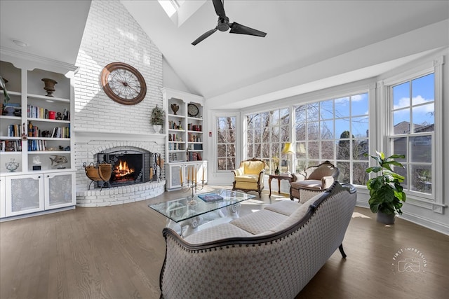 living area with built in shelves, high vaulted ceiling, wood finished floors, a brick fireplace, and ceiling fan