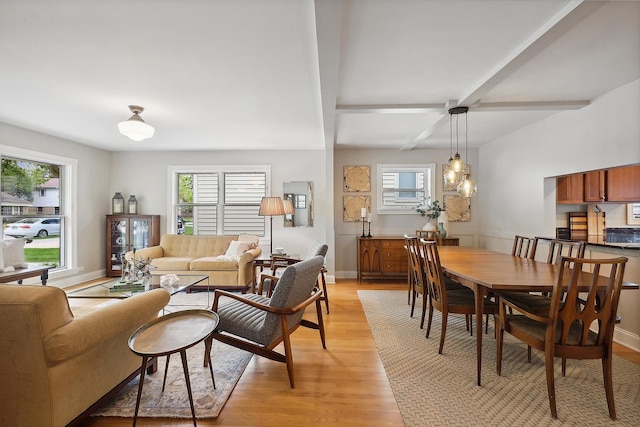 dining space with a wealth of natural light, light wood-type flooring, beam ceiling, and baseboards