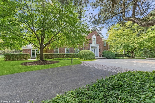 view of front of home featuring driveway, a front lawn, and brick siding