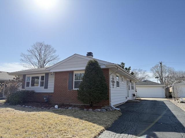 view of home's exterior featuring a yard, an outbuilding, brick siding, and a detached garage