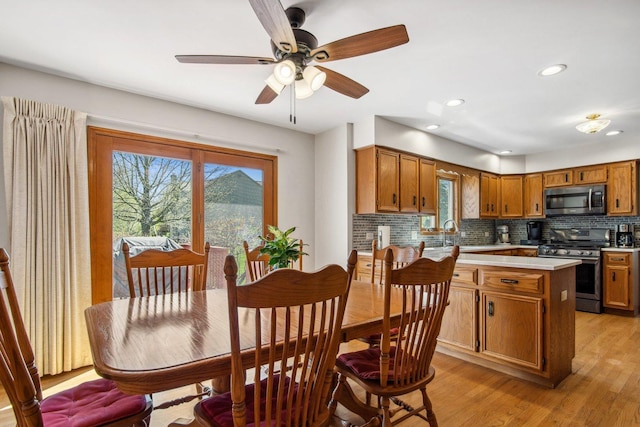 kitchen featuring light wood finished floors, stainless steel appliances, tasteful backsplash, and light countertops