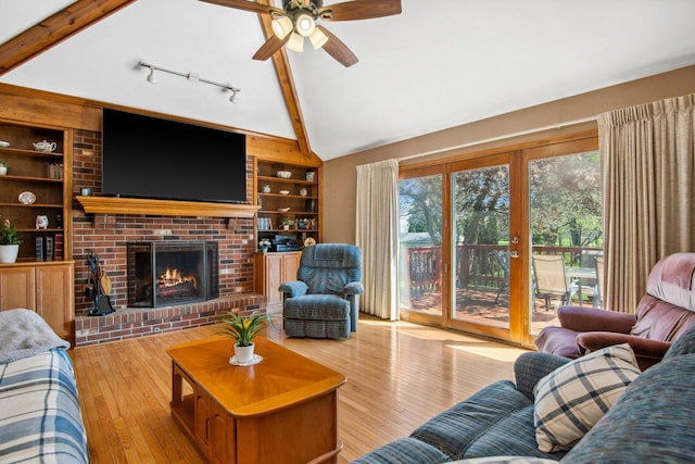 living area featuring lofted ceiling with beams, a brick fireplace, built in shelves, and hardwood / wood-style flooring