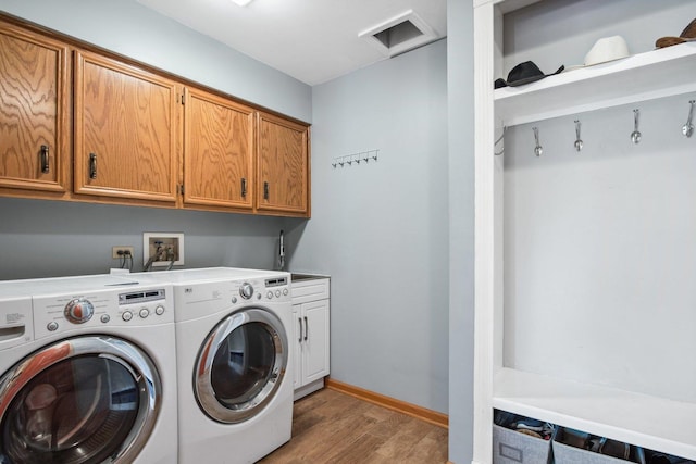 laundry area with light wood-style floors, washing machine and dryer, cabinet space, and baseboards