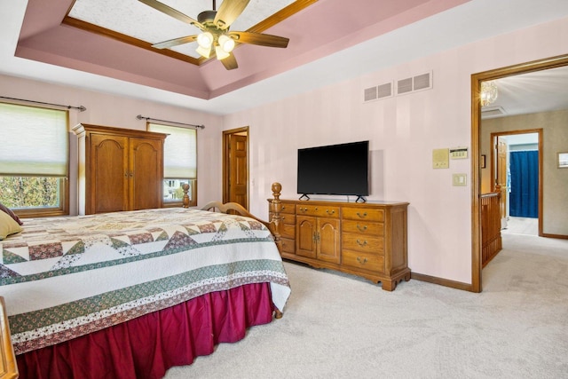 bedroom with a tray ceiling, visible vents, light carpet, ceiling fan, and baseboards