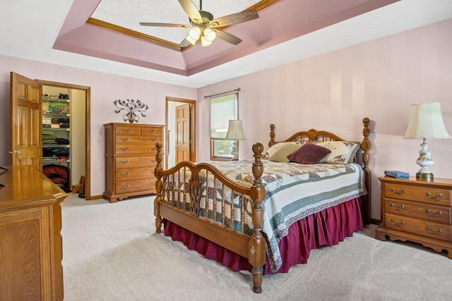 carpeted bedroom featuring a tray ceiling and a ceiling fan