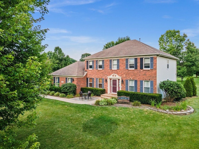 colonial house featuring a patio area, a front lawn, and brick siding