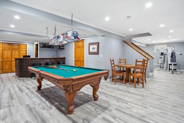 recreation room featuring a dry bar, baseboards, ornamental molding, light wood-type flooring, and recessed lighting