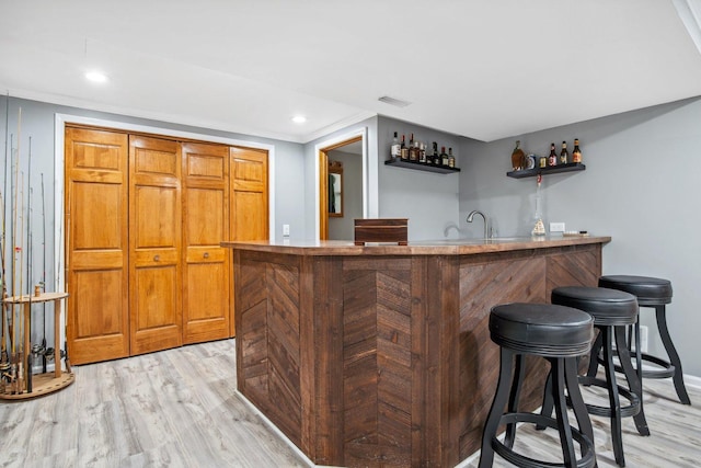 bar featuring light wood-style flooring, recessed lighting, visible vents, baseboards, and indoor wet bar