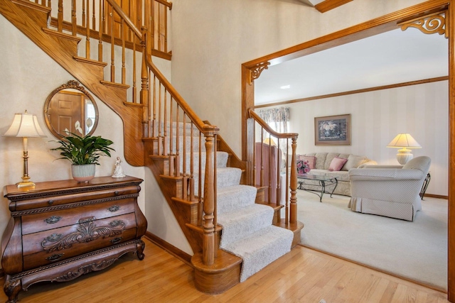 stairs featuring crown molding, wood finished floors, and baseboards