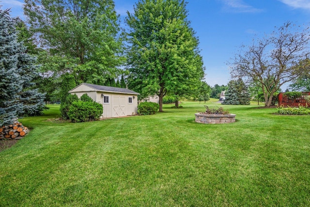 view of yard featuring an outdoor structure, a fire pit, and a storage shed